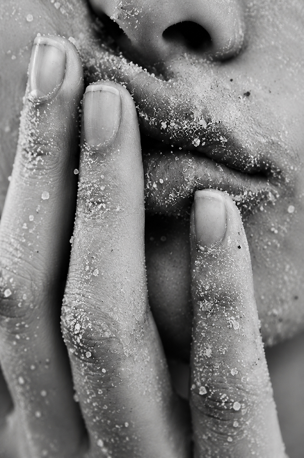 Close-up of fingers dusted with sand near lips