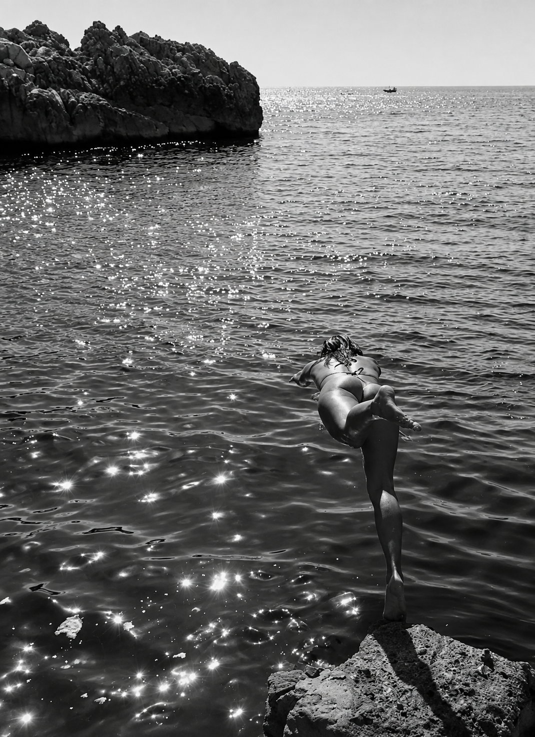 Woman diving from rocks into the ocean